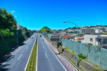 新緑の住宅街を通る高速道路。横浜市港南区の横浜横須賀高速道路。

