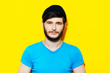 Studio portrait of young guy in blue shirt on background of yellow color.