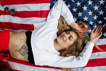 A young pretty girl lies on a large American flag