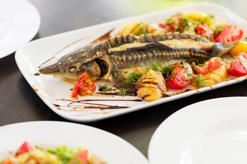 Grilled fish. Cooked fish is on the table .Grilled sturgeon fish. Grilled sturgeon fish. Sturgeon baked with vegetables. Healthy food. Soft selective focus