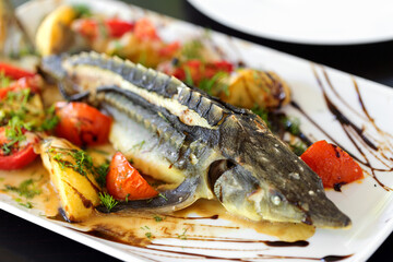 sturgeon baked with greens fruits and vegetables, soft selective focus.