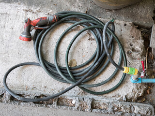 Old and dirt garden hose and water spray head.