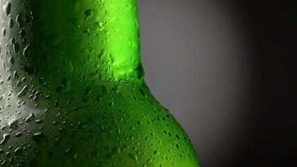 Cooled wet green beer bottle rotating against black and grey background. Beer bottle with waterdrops. Close-up shot, 4K