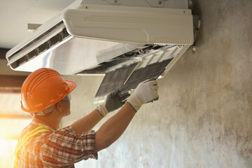 A young Asian air conditioner technician or air-conditioning installation technician is about to...
