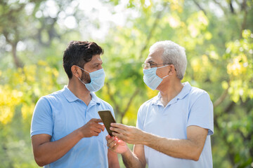 Senior people with pollution masks outside informing on smart phone about diseases.