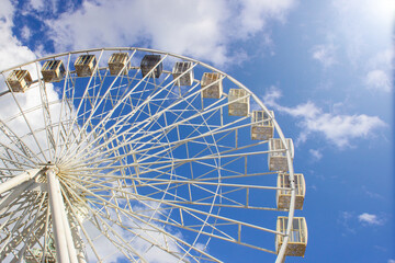 Ferris wheel on the background of blue sky and clouds