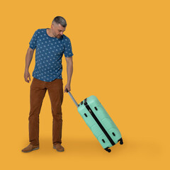 Middle-aged man carrying plastic suitcase on wheels holding it by handle. Handsome caucasian man in a t-shirt and brown trousers goes on vacation. Travel concept.