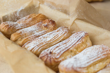 Freshly baked homemade eclairs sprinkled with powdered sugar.