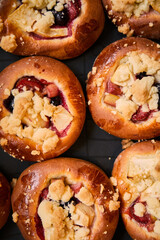 Freshly baked buns with fruits and crumble on black plate background