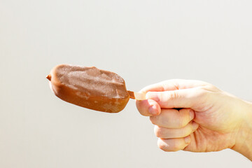 chocolate ice cream on a stick, popsicle in a man’s hand, frost