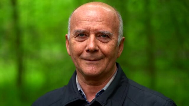 portrait of old cute man in forest, human is smiling little, blurred background - Powered by Adobe
