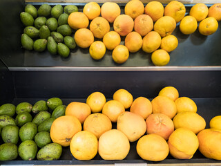 Yellow lemons and green avacados in tray on a counter in a self-service hypermarket. A fruit is a source of useful elements and vitamins. A healthy product in the daily diet of vegetarians and people.
