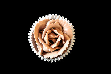 Viewed from above a rose shaped chocolate cupcake on a black background