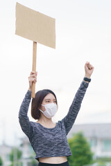 Woman holding a wood stick and raising hands high up at protesting