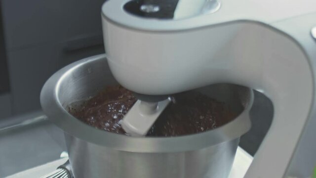 Professional chef is cooking cake. Close up of woman turn on professional mixer with chocalate dought for cake