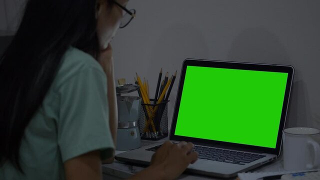An over the shoulder shot of a young woman video chatting outside with green screen on her tablet.