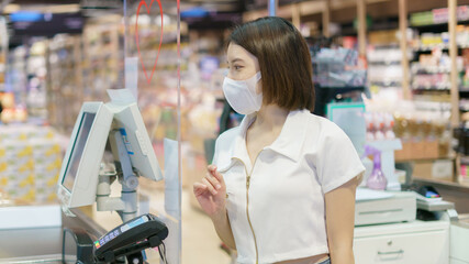 Women wearing face mask to prevent Coronavirus (Covid-19) and payment at cashier counter in supermarket.