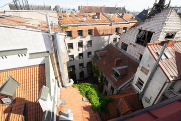 Fototapeta premium Top view of yard in old town of Riga. Old exterior of modern architecture buildings. Red tile roof. Broken window.