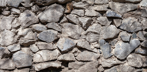 background, texture of a gray stone wall made of large stones, panorama
