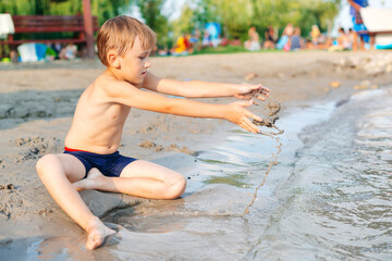 Sunny summer day. Leisure, games and vacation. Cute kid playing game at the beach.
