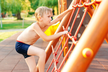 Fototapeta premium Cute boy having fun at the playground on the beach. Summer vacations.