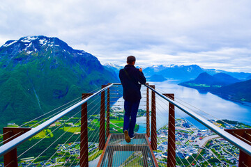 Hiking Rampestreken. Tourist man on the Rampestreken Viewpoin. Panoramic landscape Andalsnes city in Norway.