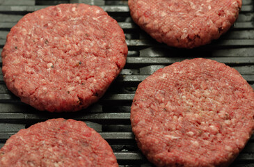 Seasoned beef burgers with a pinch of salt and black pepper on the grill