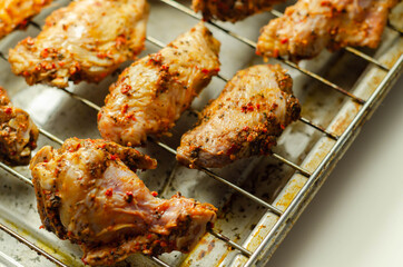 Raw chicken wings with a rendang style rub made with chilli and garlic on the grill tray