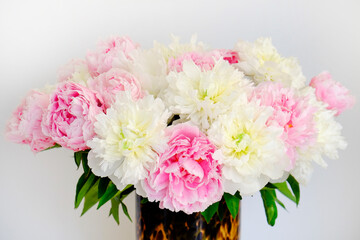Studio shot of peonies in glass vase with leopard pattern, white background with a lot of copy space for text. Feminine floral composition. Close up, top view, backdrop, flat lay.