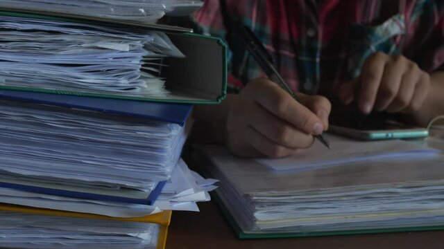 defocused accountant working in office at night, dark binders full of documents