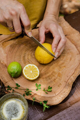 White female hands cutting a lemon on a wooden table. 