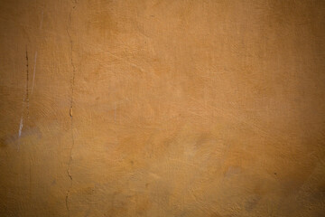 Grunge plastered wall with cracks. Texture, abstract background of colored stucco of orange or yellow.