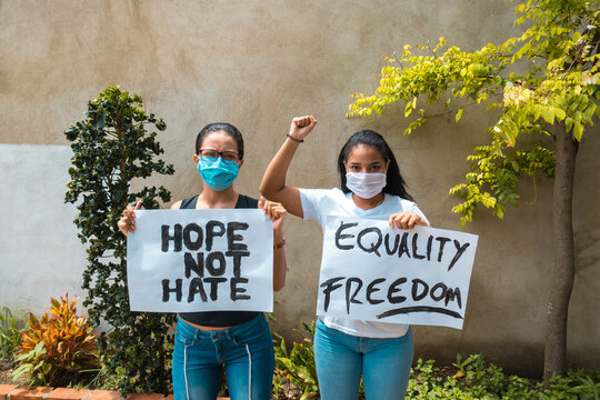 Two African-American women protesting holding signs - Powered by Adobe