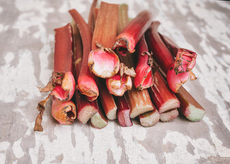 Red stems of rhubarb on an old rustic wooden table. Its sour taste makes it a perfect ingredient in jams, crumbles, pies, and other desserts.