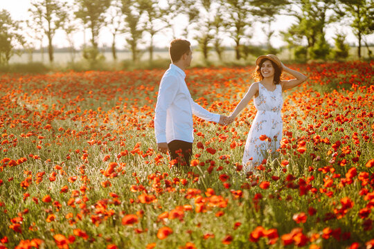 Loving couple in the poppy field. Loving couple hug one another during romantic date in poppy field. Enjoying time together. The concept of youth, love and lifestyle.