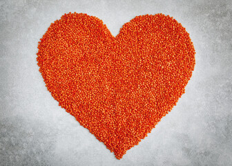 Love heart with red lentils on a light gray background.