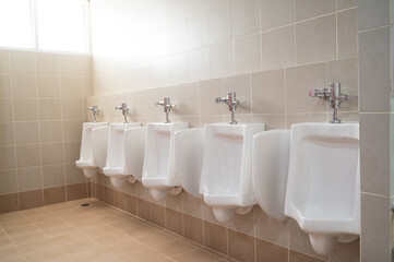 Empty row of urinals men and boy at the public toilet.White ceramic urinals for man in the gentleman rest room.