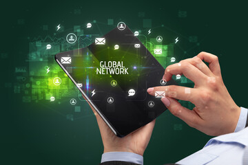 Businessman holding a foldable smartphone with GLOBAL NETWORK inscription, social networking concept
