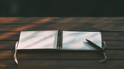 An open paper notebook with ribbons and a pen for writing planning on a textured wooden table