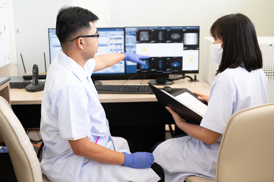 Asian radiologists shows the patient CT scan image at display for explaining  treatment patient information to doctor in x-ray room.High technology for planing medical treatment equipment concept.