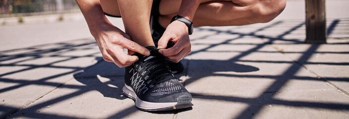 Girl tying slippers on the floor to go running. Panorama picture