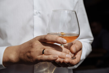 A glass with brinides in male hands. Glass with an alcoholic drink.