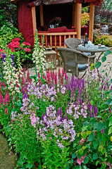 The patio area and terrace in aquatic garden with colourful flower border and summer house