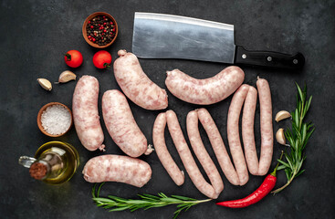 different raw sausages with spices on a stone background