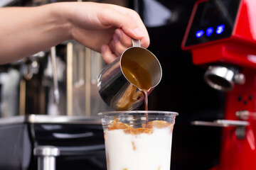 Ice coffee preparation preparation service concept. Barista makes espresso in a cafe; close-up of milk pouring. Freshly ground coffee close-up