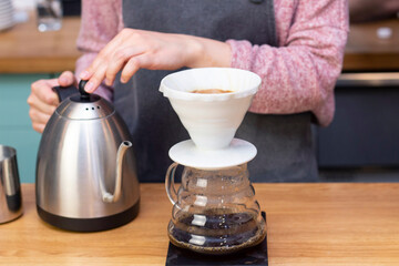 barista makes espresso using a funnel. The process of making coffee in the prover. Spilling coffee through the filter funnel from the kettle.