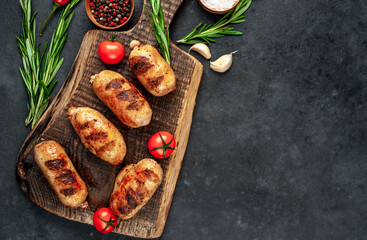 Grilled chicken sausages with spices on a stone background 
with copy space for your text