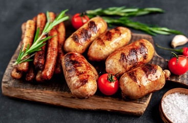 Different grilled sausages with spices and
rosemary, served on a cutting board on a stone background