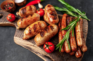 Different grilled sausages with spices and
rosemary, served on a cutting board on a stone background