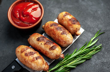 Grilled sausages over a meat knife on a stone background
